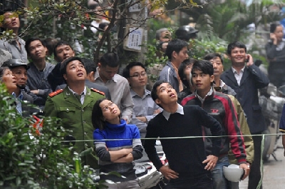 Người dân đứng ngoài khu vực đã chăng dây lo lắng nhìn lên ngôi nhà bị nghiêng